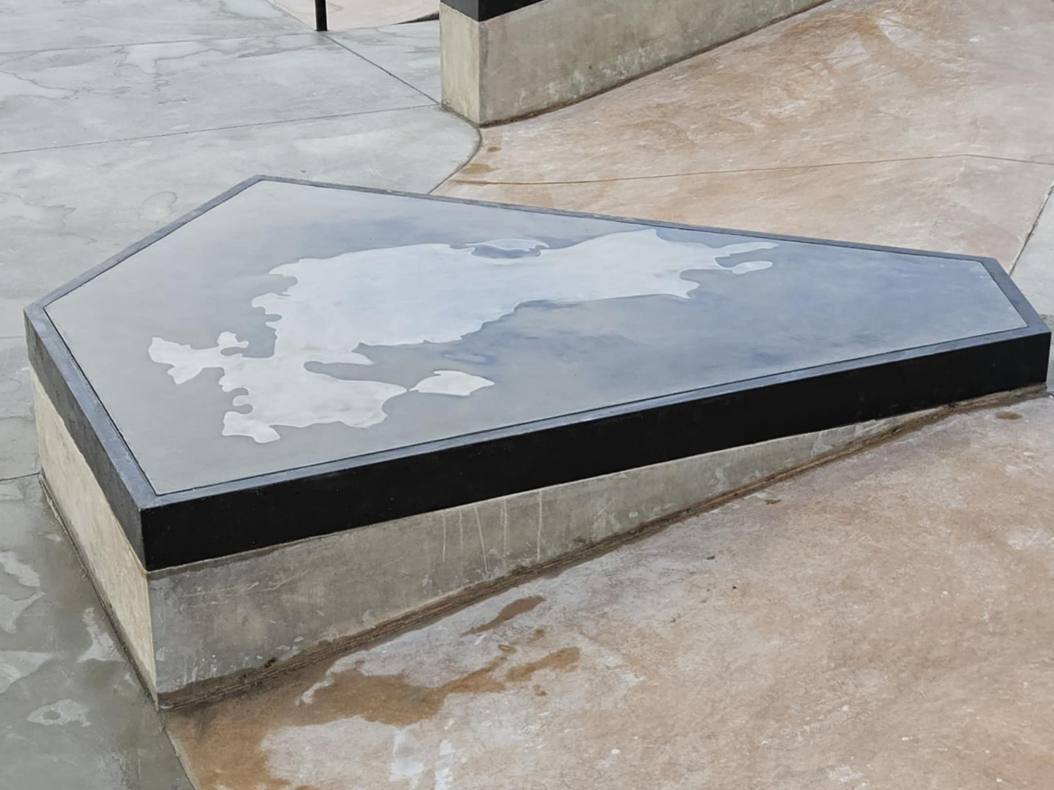 The stainless-steel map of Lopez Island set flush into a black-edged ledge at Lopez Island Skatepark.