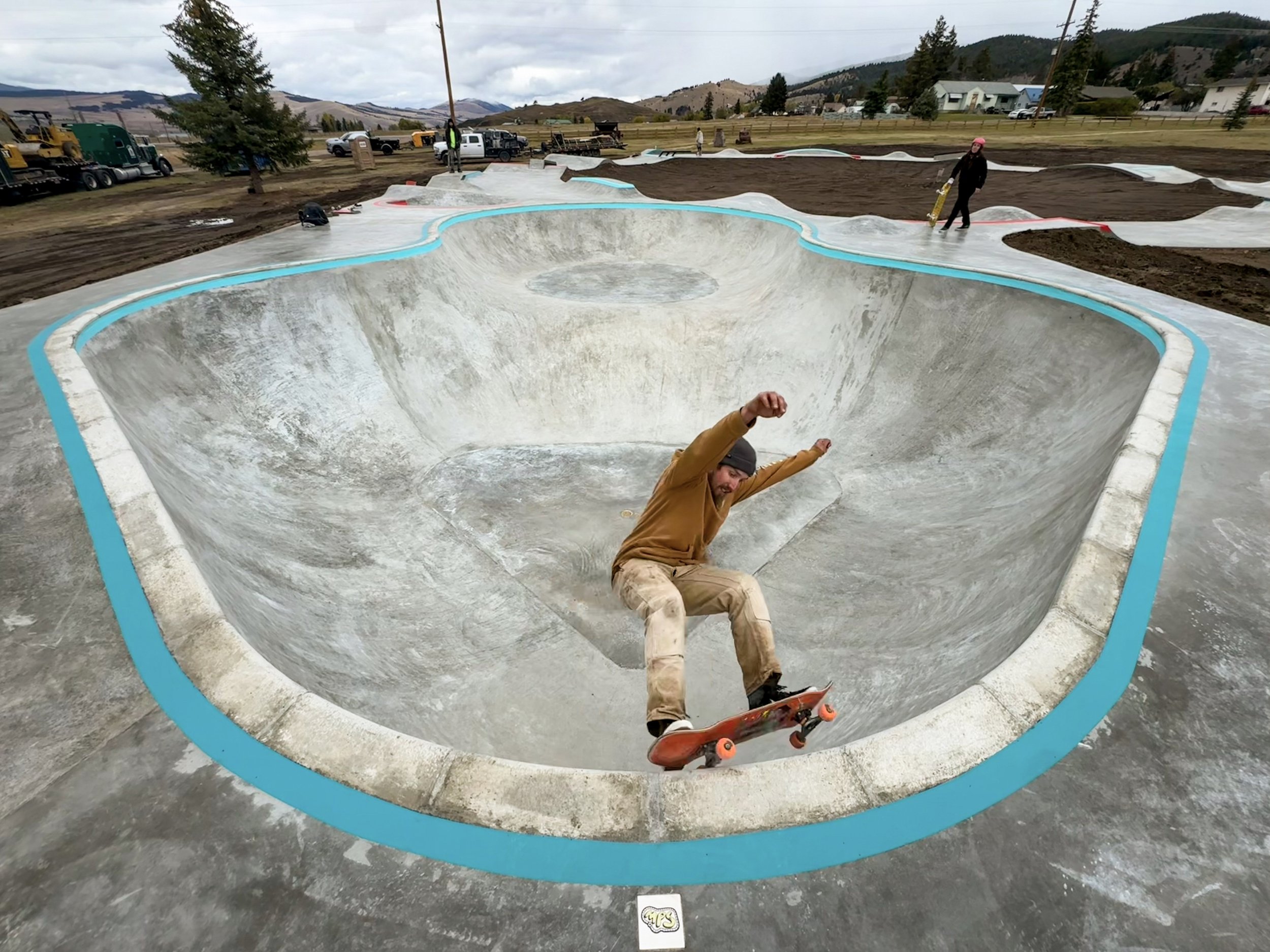 A skater carving the lip of Philipsburg's new bowl, teal paint on the coping and the mountains behind it.