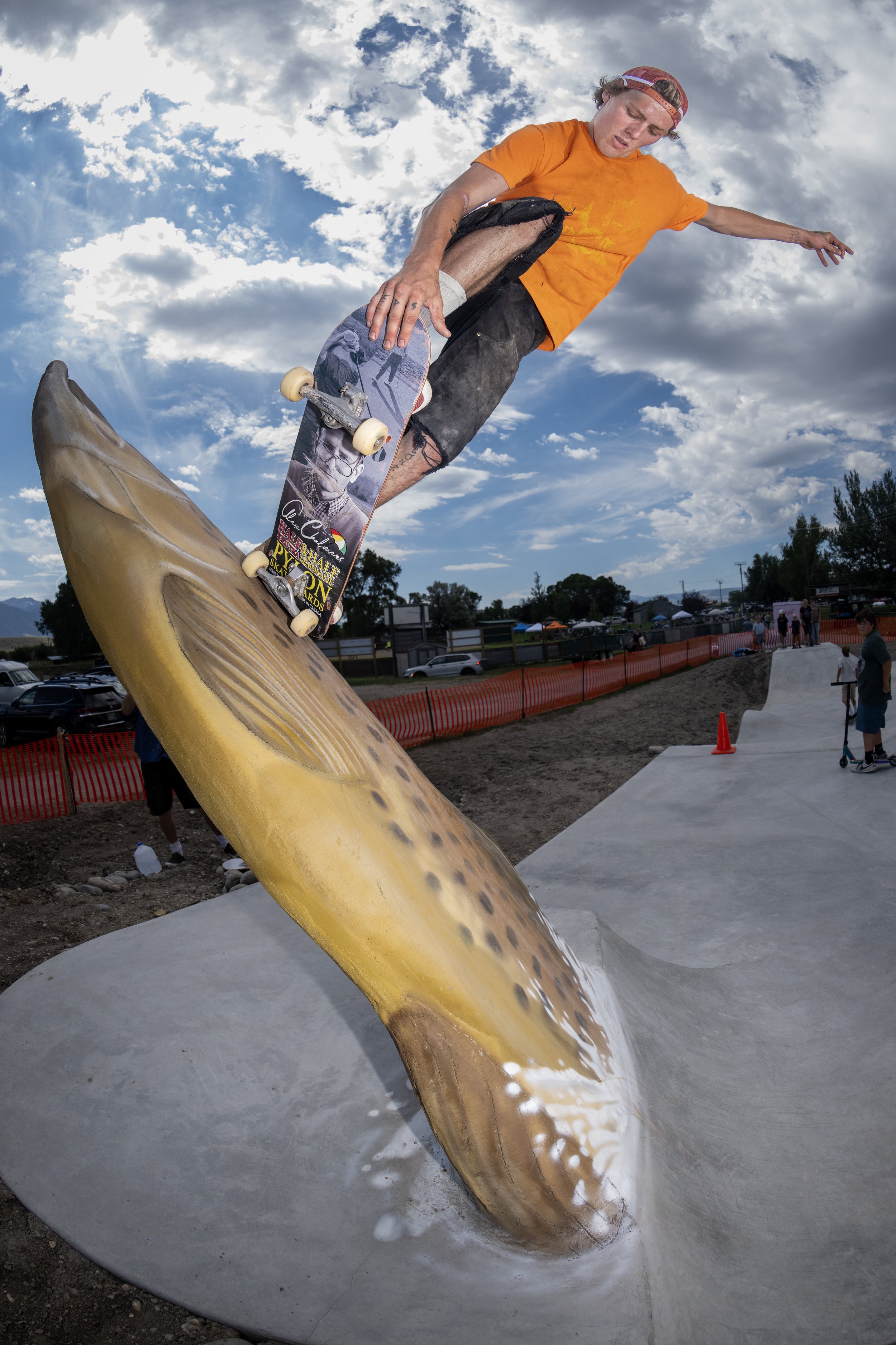 A skater grinding up the back of the rideable metal trout at Ennis, under a big Montana sky.