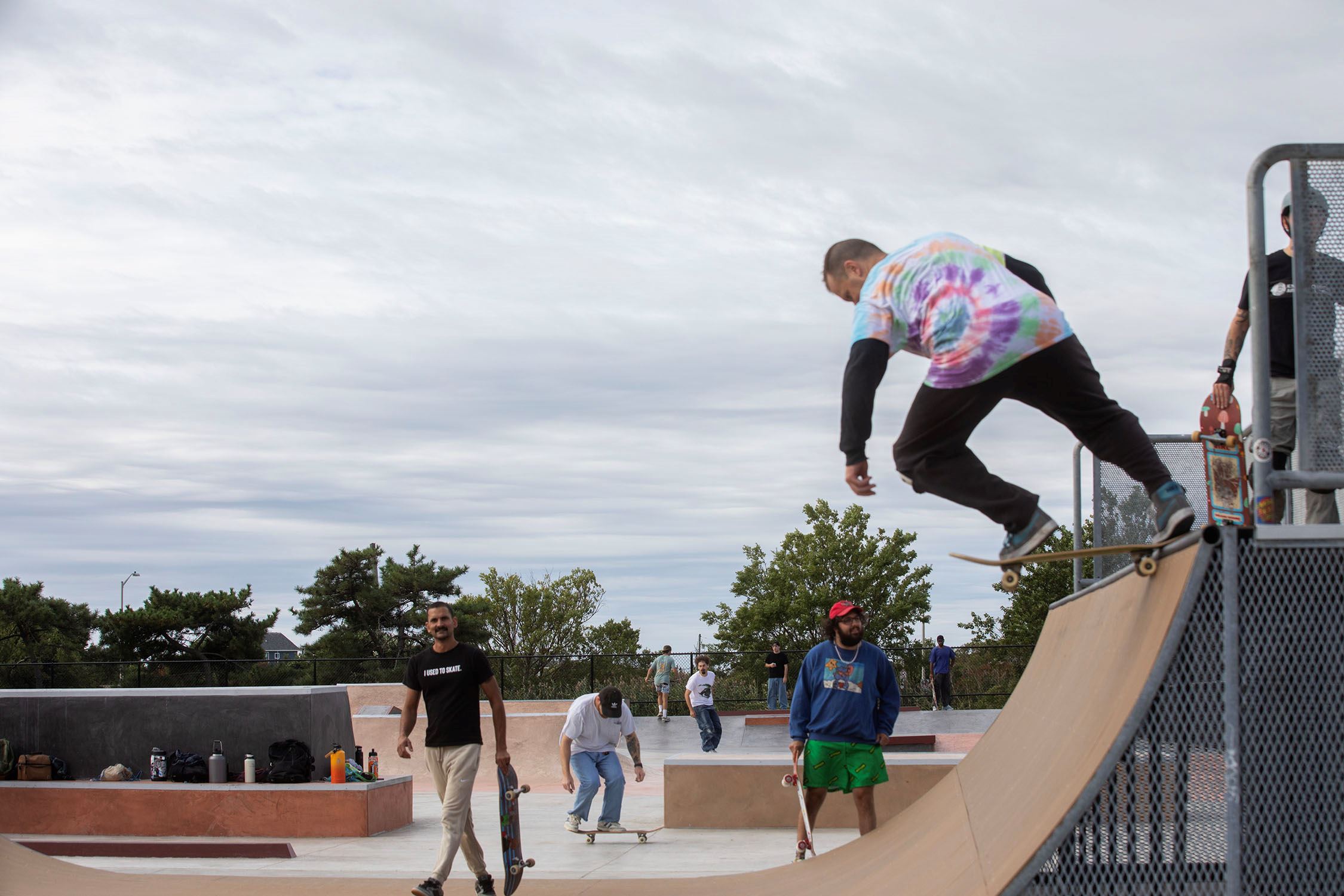 A skater coming off the top of a quarter pipe at the new Tanner Park, with the opening-day crowd skating and watching below.